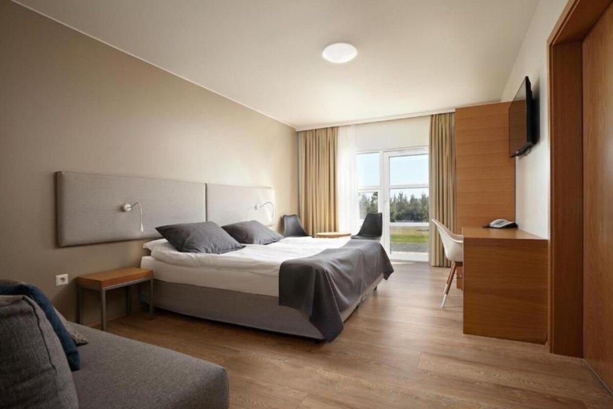 Una habitación de hotel moderna con cama, mesitas de noche, escritorio, silla y televisión.