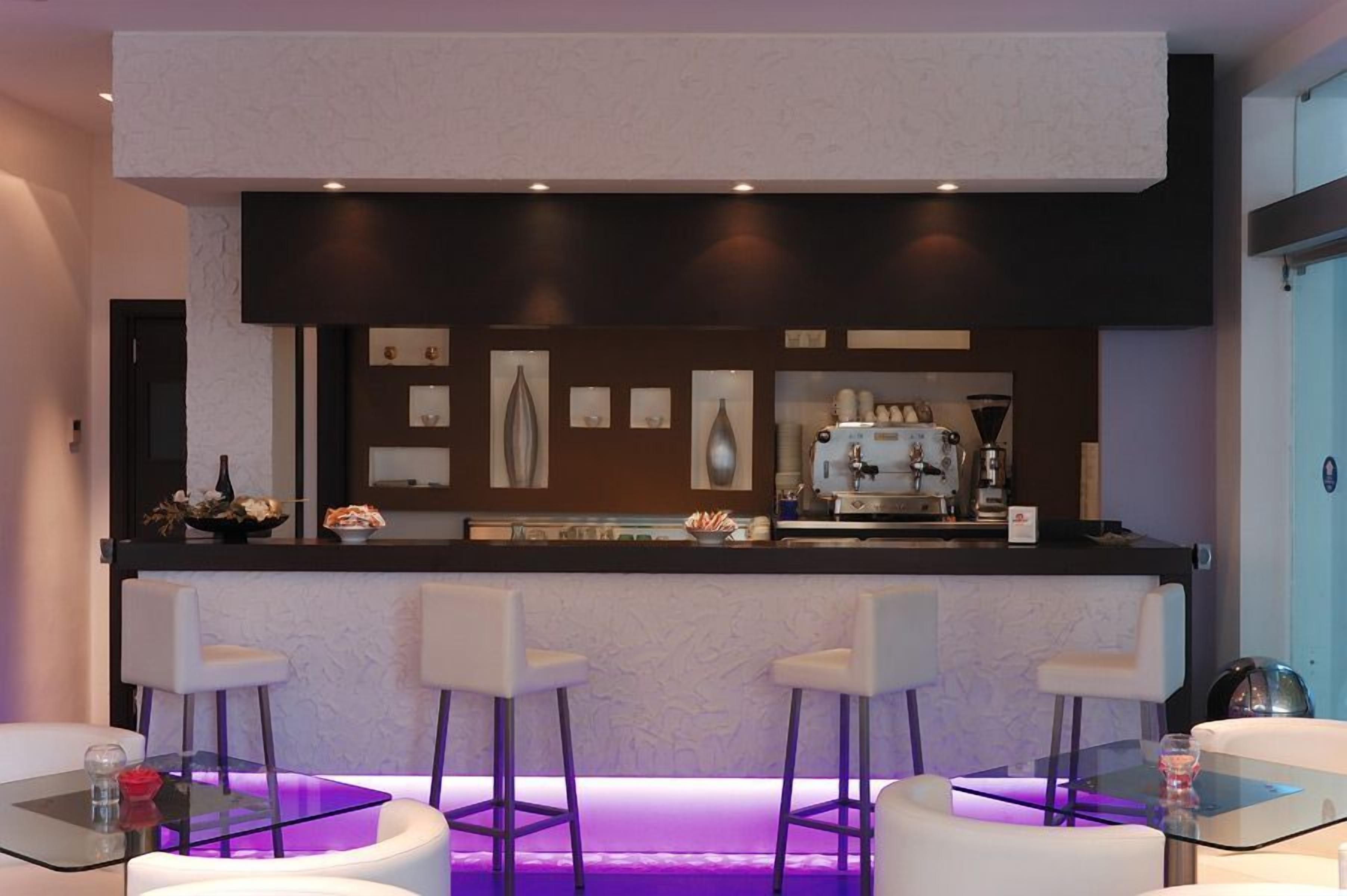 Uma área de bar moderna com balcão, banquetas e uma máquina de café.