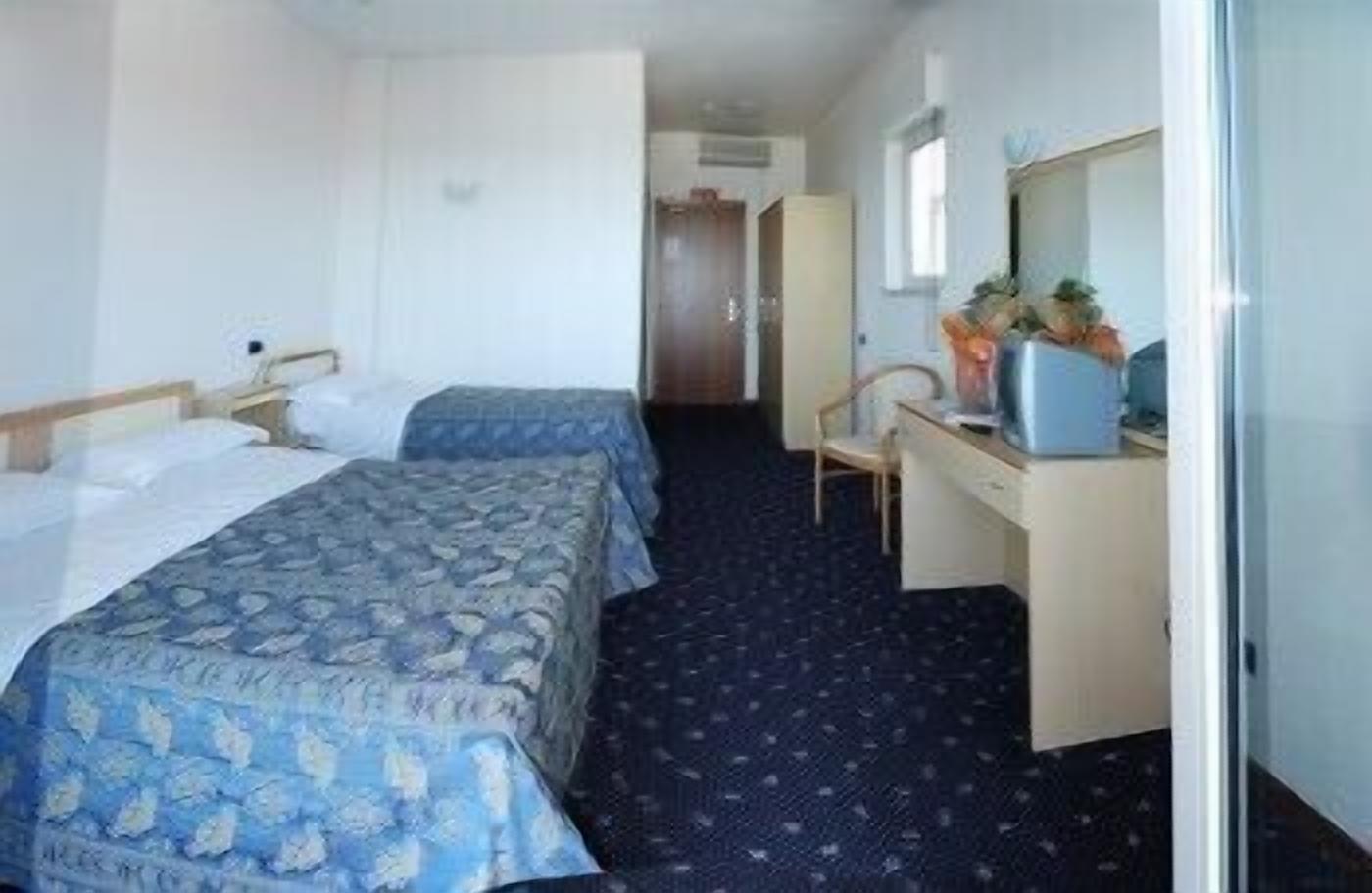 A hotel room with two beds, a desk, and a chair.