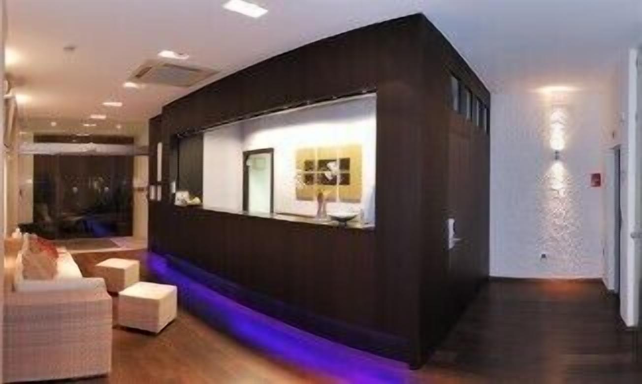 A modern reception area with a curved desk, a seating area with a sofa and chairs, and a blue-lit pathway.