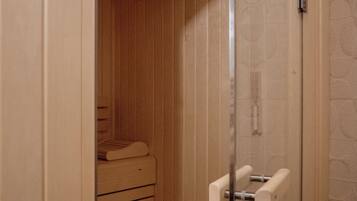 Un sauna équipé d’un banc et d’une porte en verre donnant sur un espace douche.