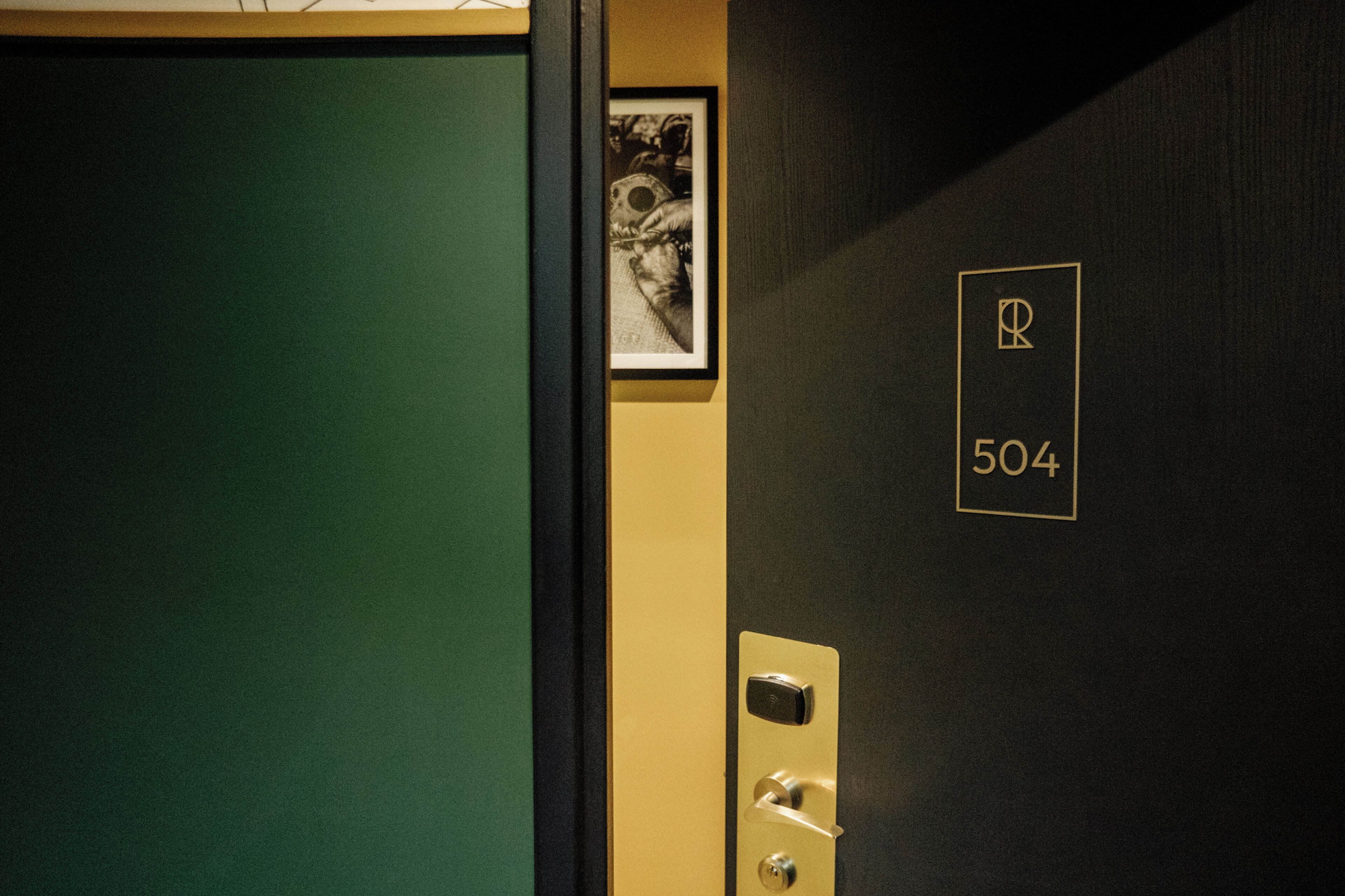A hotel room door with a number 504 sign, a framed picture, and a door handle.