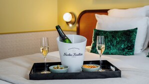 Habitación de hotel con una cama, una bandeja con champán, dos copas de champán y un cuenco de aperitivos.