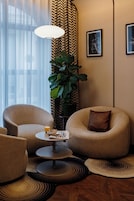 A modern living room with two armchairs, a small round table, and a large plant.
