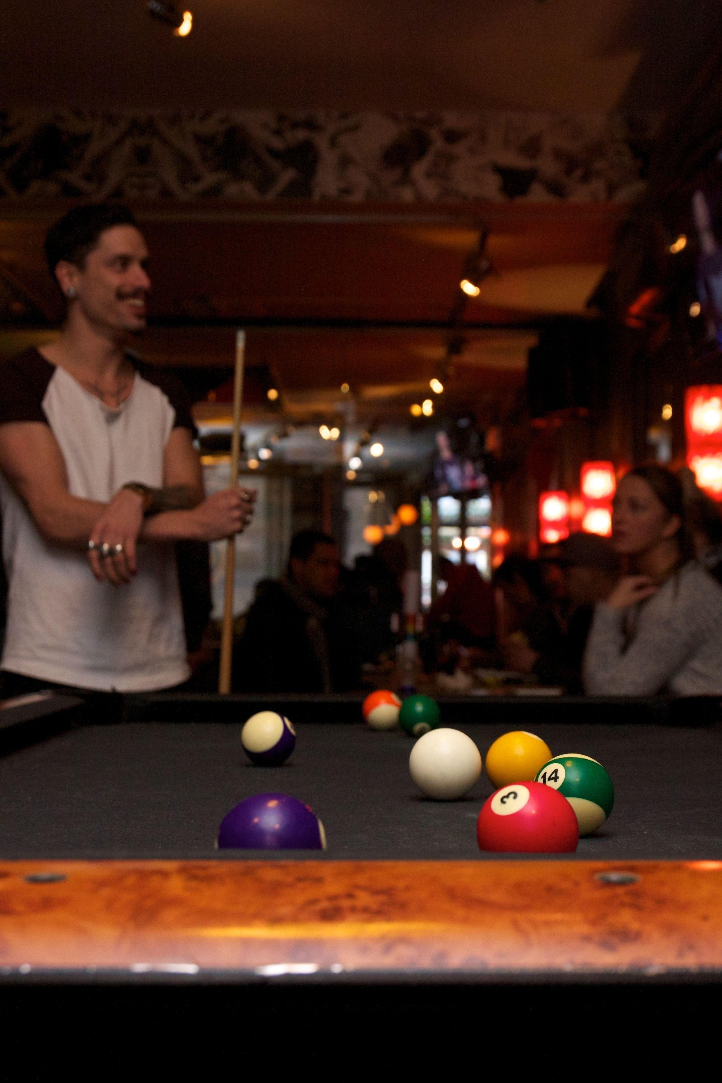 A pool table with balls and a person holding a cue stick.