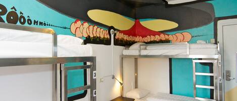 Habitación con literas, un mural en la pared, una mesita de noche y una puerta.