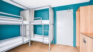 Ein Zimmer mit Etagenbetten, einem Kleiderschrank und einer Tür.