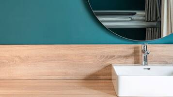 Ein Badezimmer mit einem Holzkosmetikschrank, einem weißen Waschbecken und einem runden Spiegel.