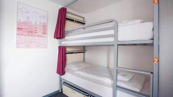 A bunk bed with two levels, each with a mattress and pillows. There is a poster on the wall depicting a cityscape.