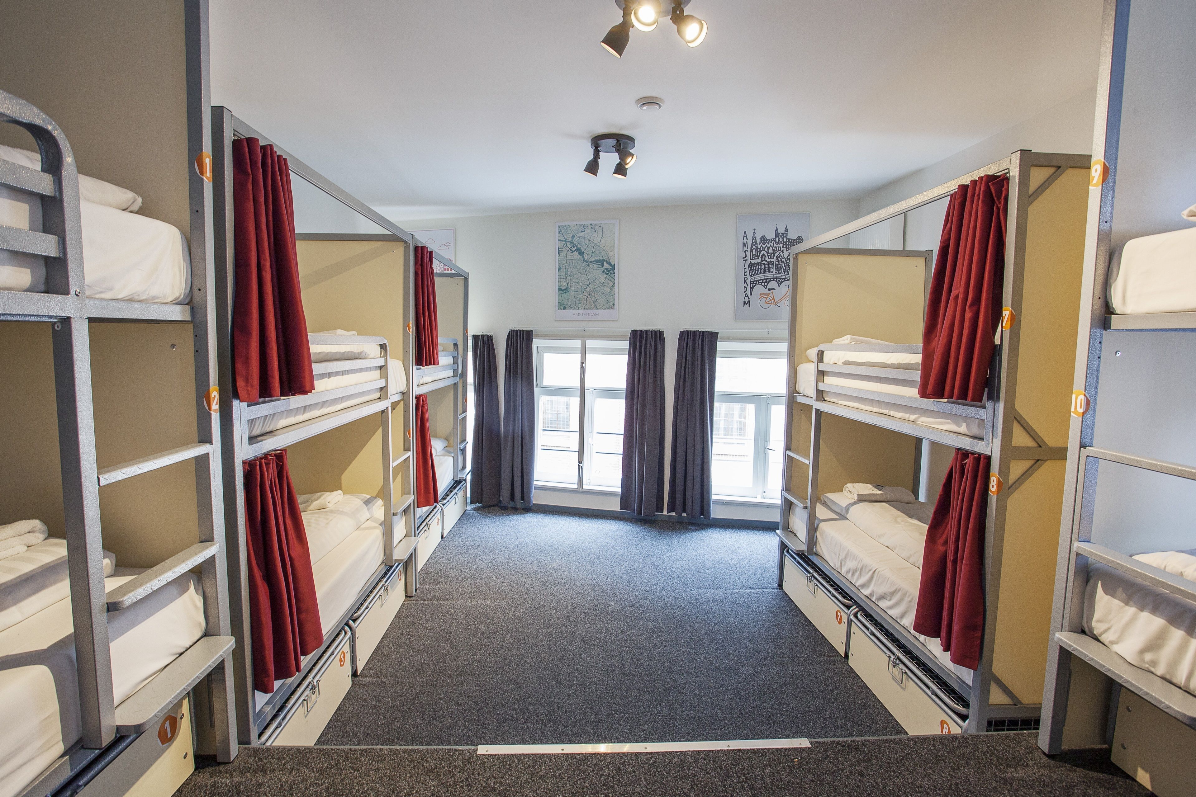 Ein Schlafsaalzimmer mit Etagenbetten, Teppichboden und Vorhängen.