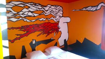 Een kamer met een bed, een muurschildering en een raam.