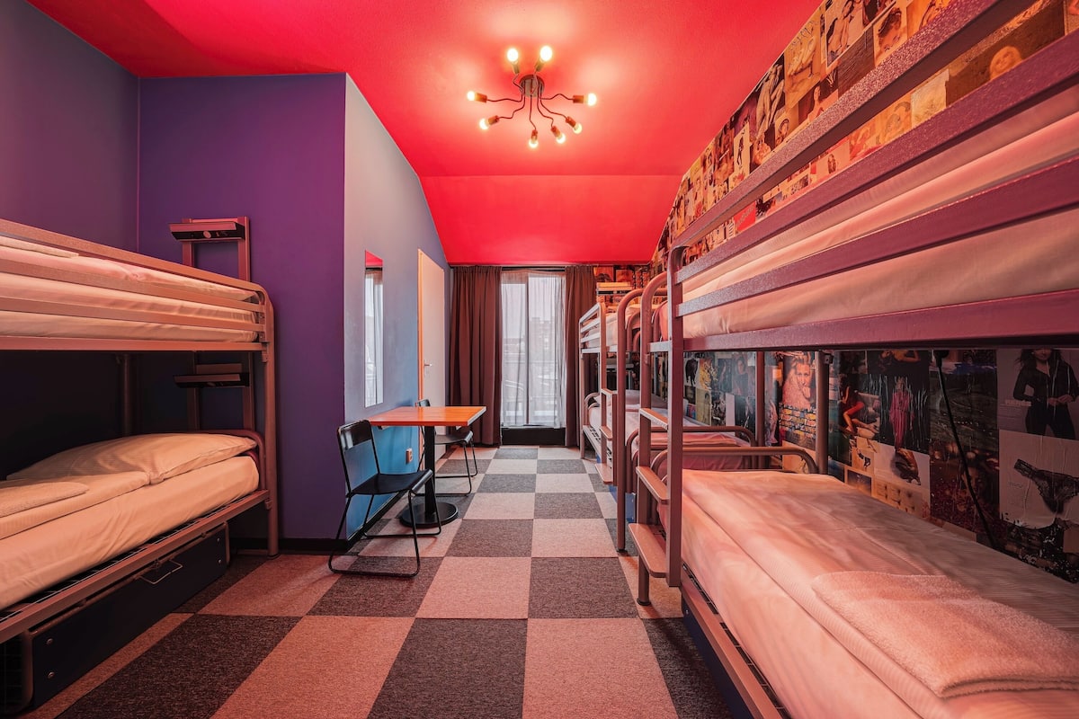 A dormitory room with bunk beds, a desk, and a chair.