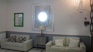 A room with two sofas, a table, a lamp, a mirror, a ceiling light fixture, and a wall-mounted fire alarm. - D'este (Rome)