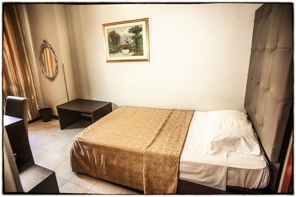 Un dormitorio ordenado con cama, mesita de noche y un cuadro en la pared.