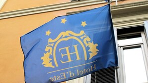 A blue flag with a golden emblem and the text "Hotel b' Este" on a building facade. - D'este (Rome)