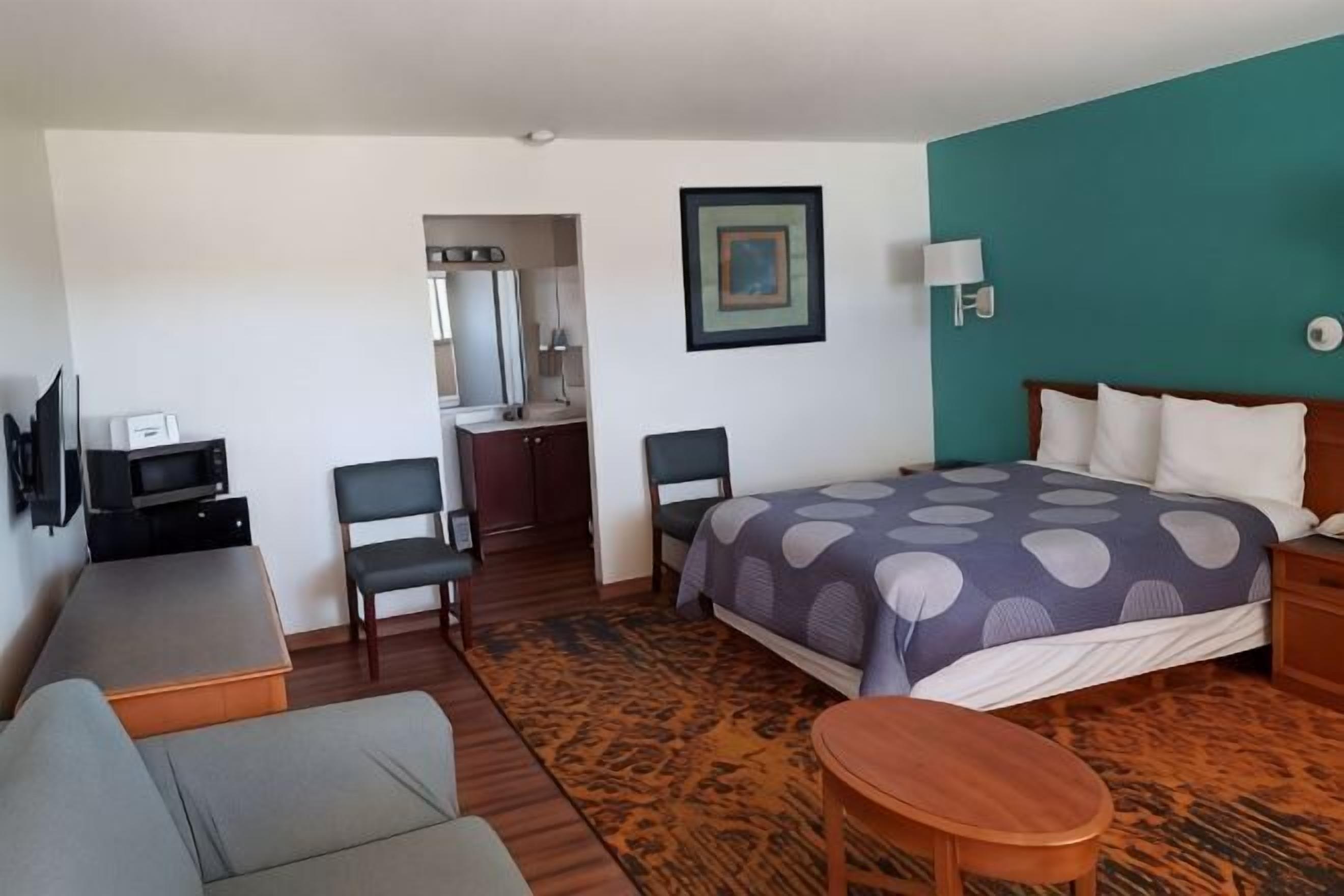 Een hotelkamer met een bed, een bureau, een stoel, een televisie en een bijzettafeltje.