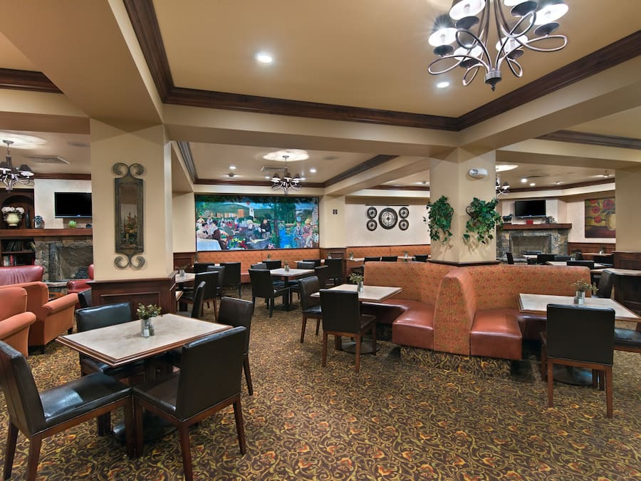 A restaurant with booths, tables, and chairs. There are decorative wall elements and a television.