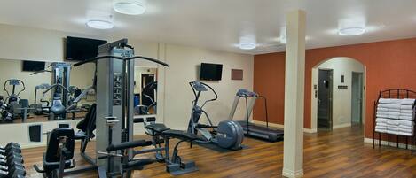 A gym with exercise equipment, a mirror, and a towel rack.