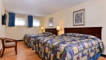 A hotel room with two beds, a desk, and a chair.