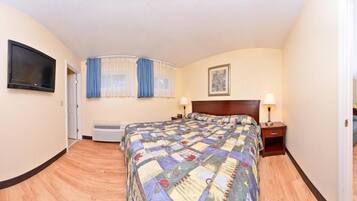 Hotelkamer met een groot bed, een aan de muur bevestigde televisie, een bureau met stoel en een raam met gordijnen.