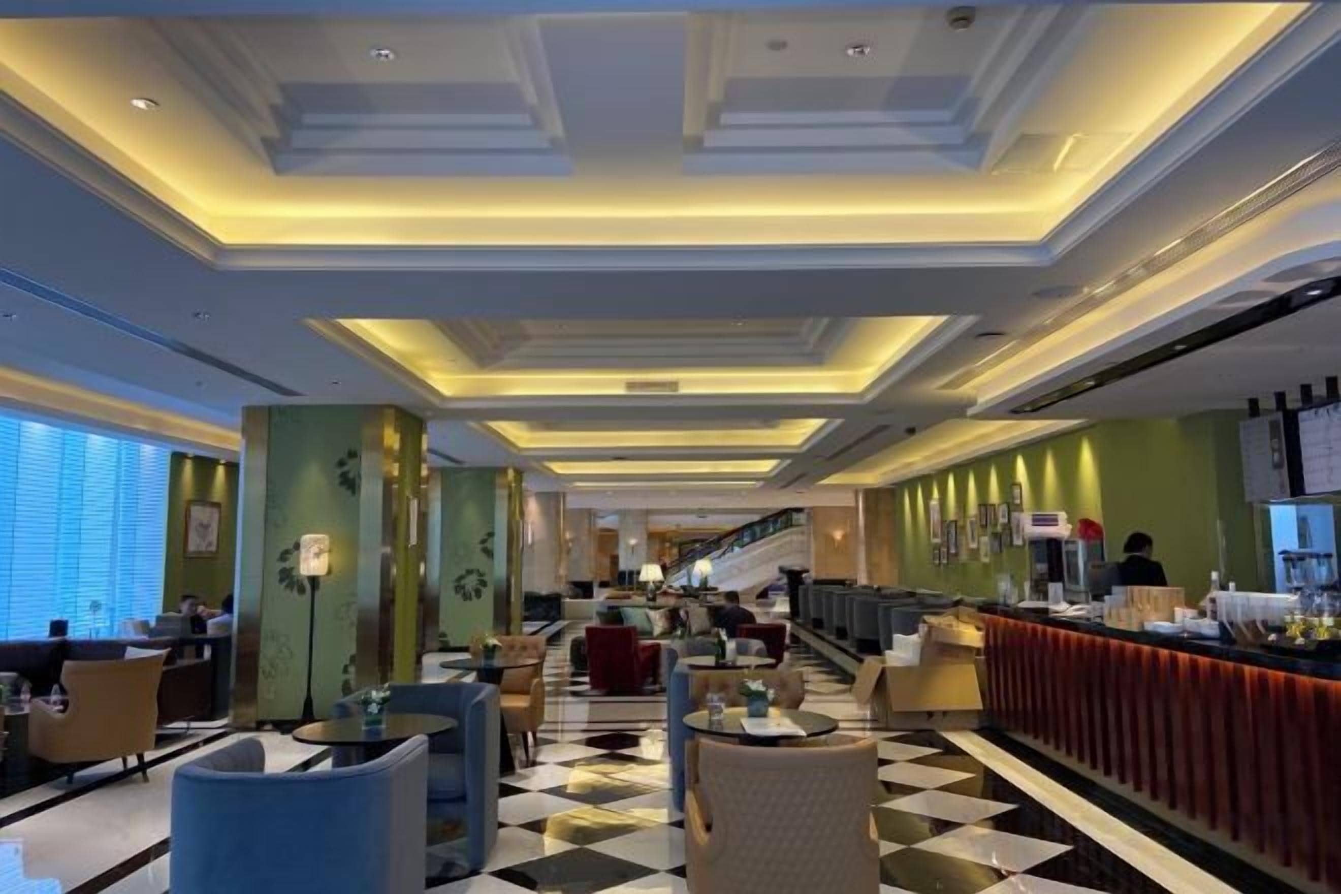 A hotel lobby with a checkered floor, a staircase, and seating areas.