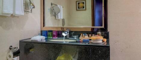 A bathroom with a black countertop, a mirror, a sink, and a towel rack.
