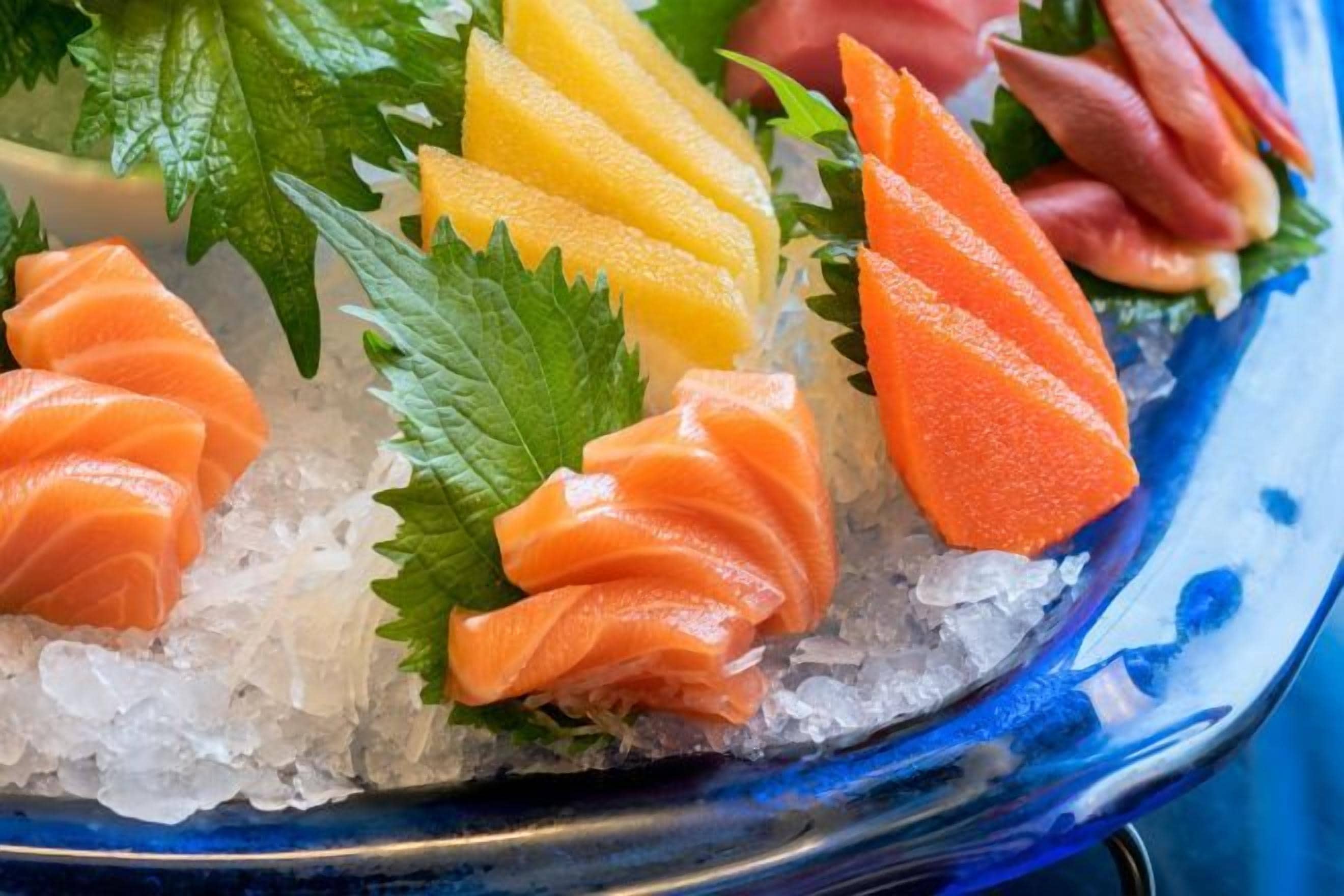En skål med sushi med lax, mango och inlagd ingefära.