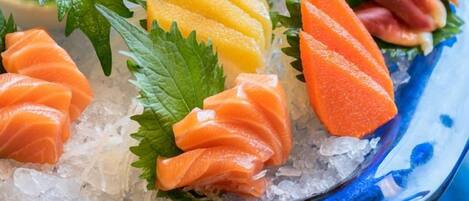 En skål med sushi med lax, mango och inlagd ingefära.