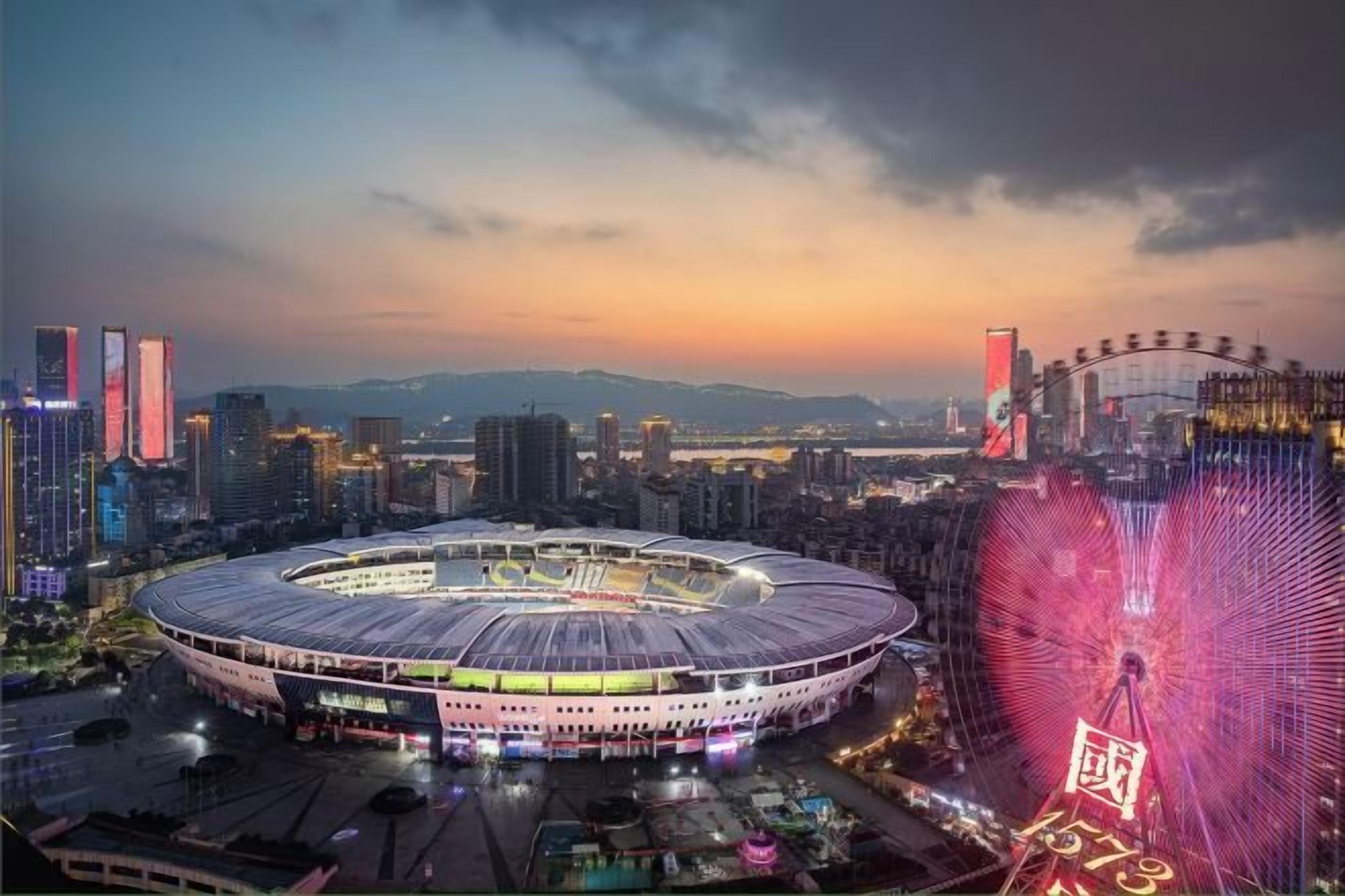 A stadium with a circular design, surrounded by high-rise buildings and a large Ferris wheel.