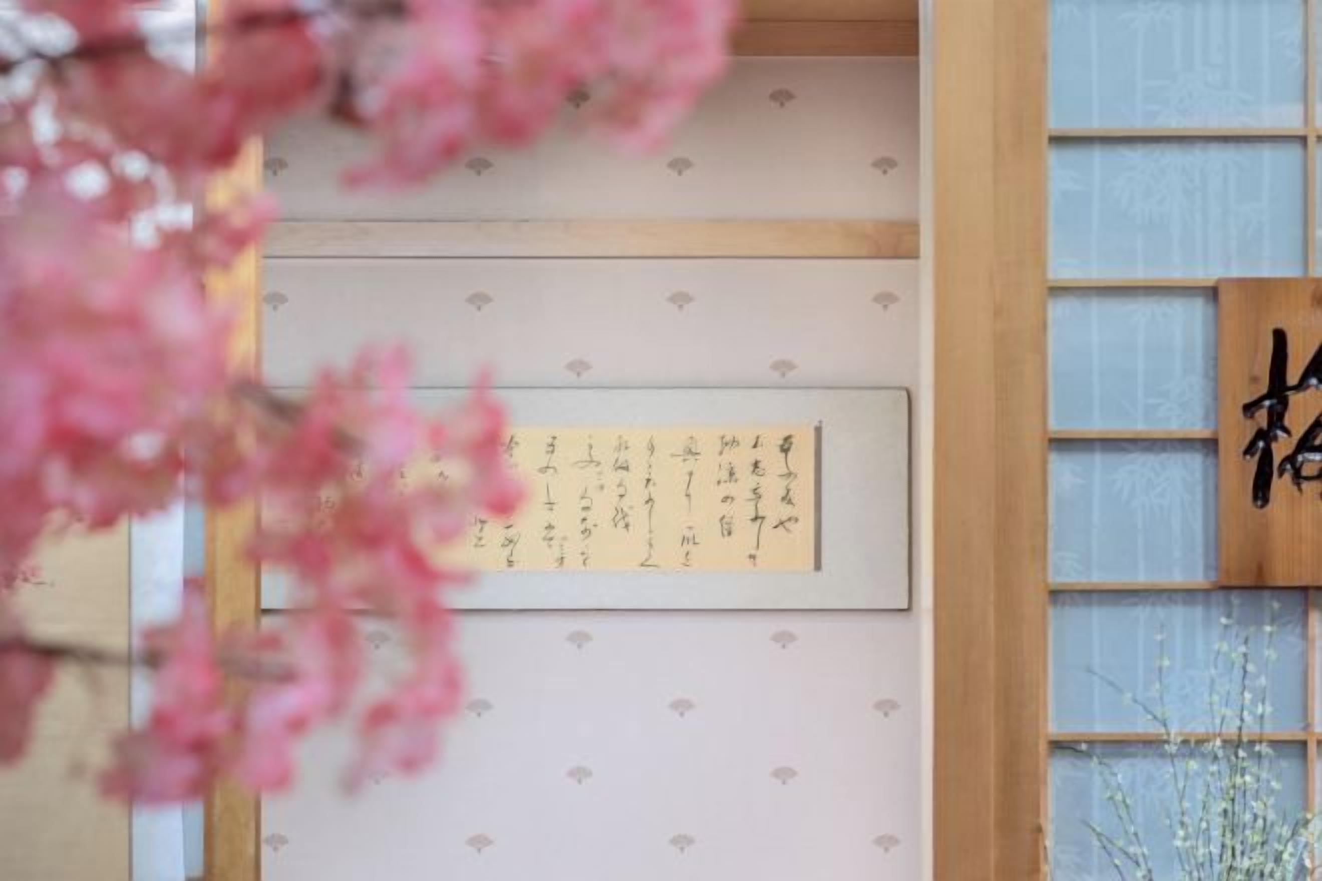 A traditional Japanese room with tatami flooring, a shoji screen, and a calligraphy piece on the wall.