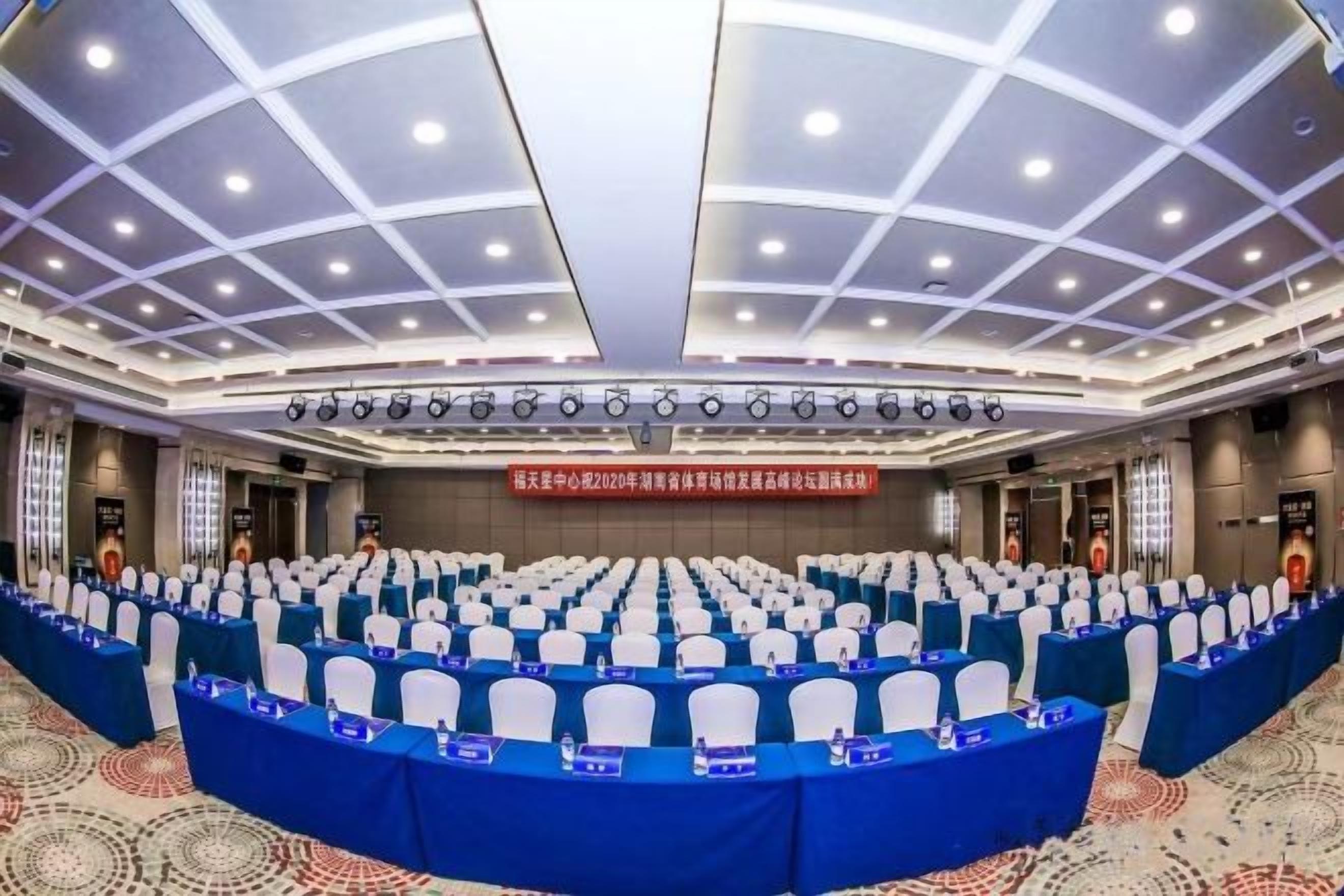 A conference room with a long table, multiple chairs, and a stage with a podium.