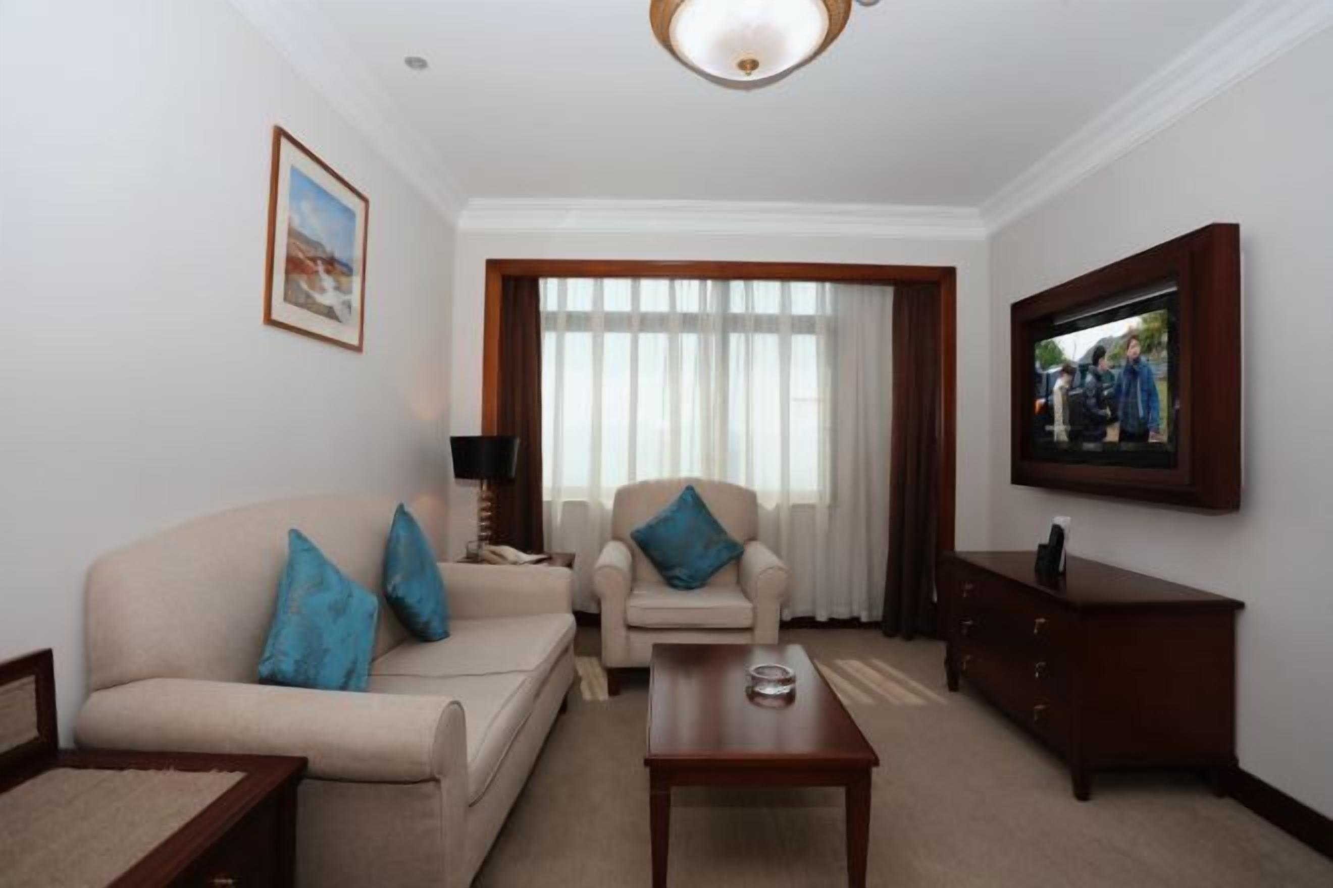 Una sala de estar con sofá, sillón, mesa de centro, televisor y aparador.