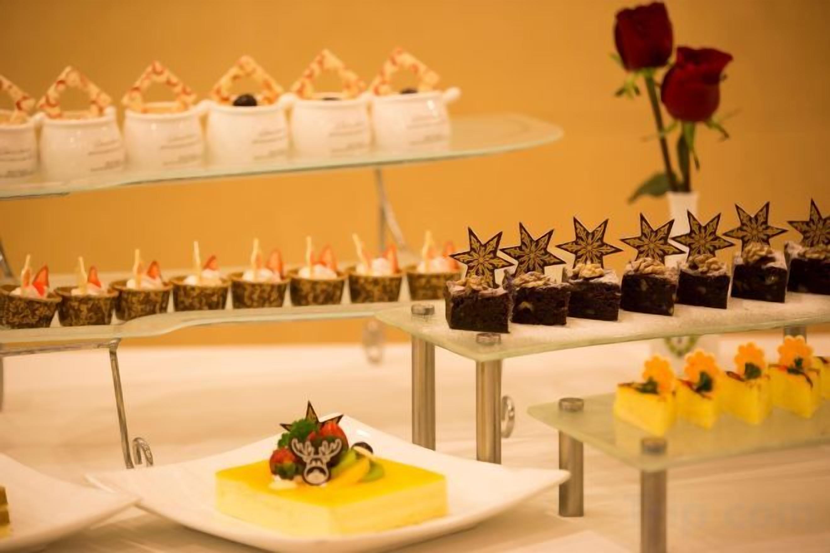 Une présentation de desserts comprenant divers gâteaux et pâtisseries disposés sur des présentoirs en verre.