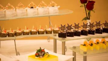 Une présentation de desserts comprenant divers gâteaux et pâtisseries disposés sur des présentoirs en verre.