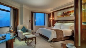 A hotel room with a bed, a desk, a chair, and a view of the city. - Changsha Jinyuan Yangguang Hotel (Wu Yi Square Helong Stadium) (Changsha)