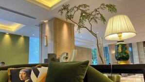 A modern lobby with a green sofa, a decorative lamp, and a large tree. - Changsha Jinyuan Yangguang Hotel (Wu Yi Square Helong Stadium) (Changsha)
