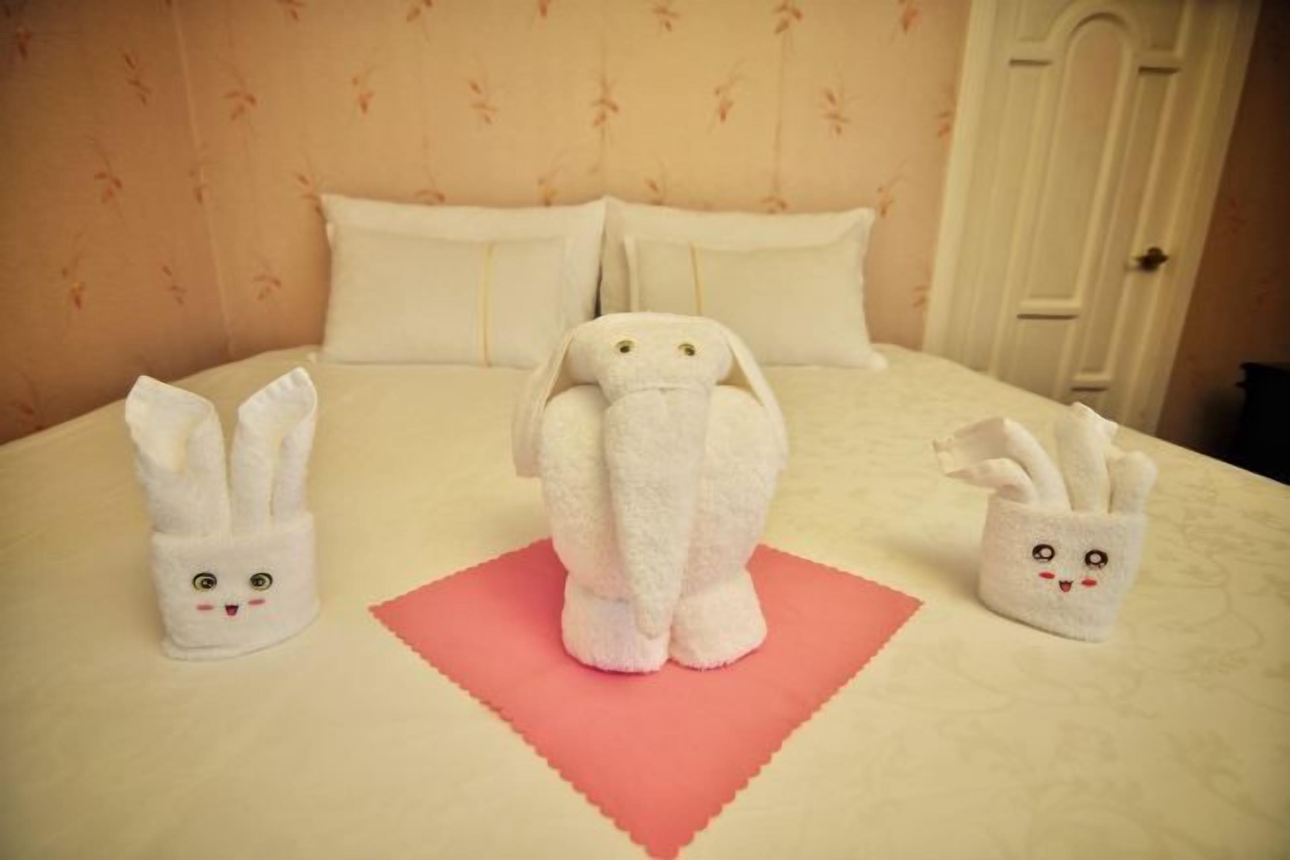 Una habitación de hotel con cama, almohadas y una decoración de toallas.