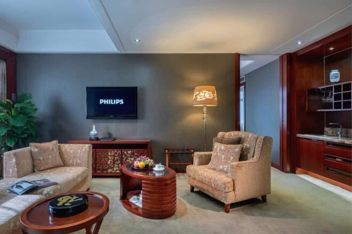 A living room with a sofa, armchair, coffee table, lamp, TV, and decorative items.