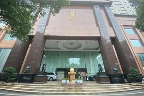 A hotel entrance with a large, gold-colored entrance feature, a car parked in front, and a statue on the right. - Changsha Jinyuan Yangguang Hotel (Wu Yi Square Helong Stadium) (Changsha)