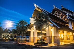 A building with a traditional architectural style, featuring a prominent entrance with a covered walkway and palm trees.