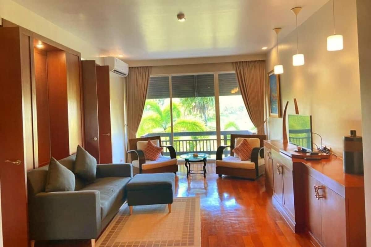 A modern living room with a sofa, armchairs, a coffee table, and a TV.