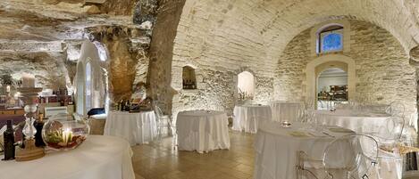 An underground restaurant with stone walls and tables set for dining.