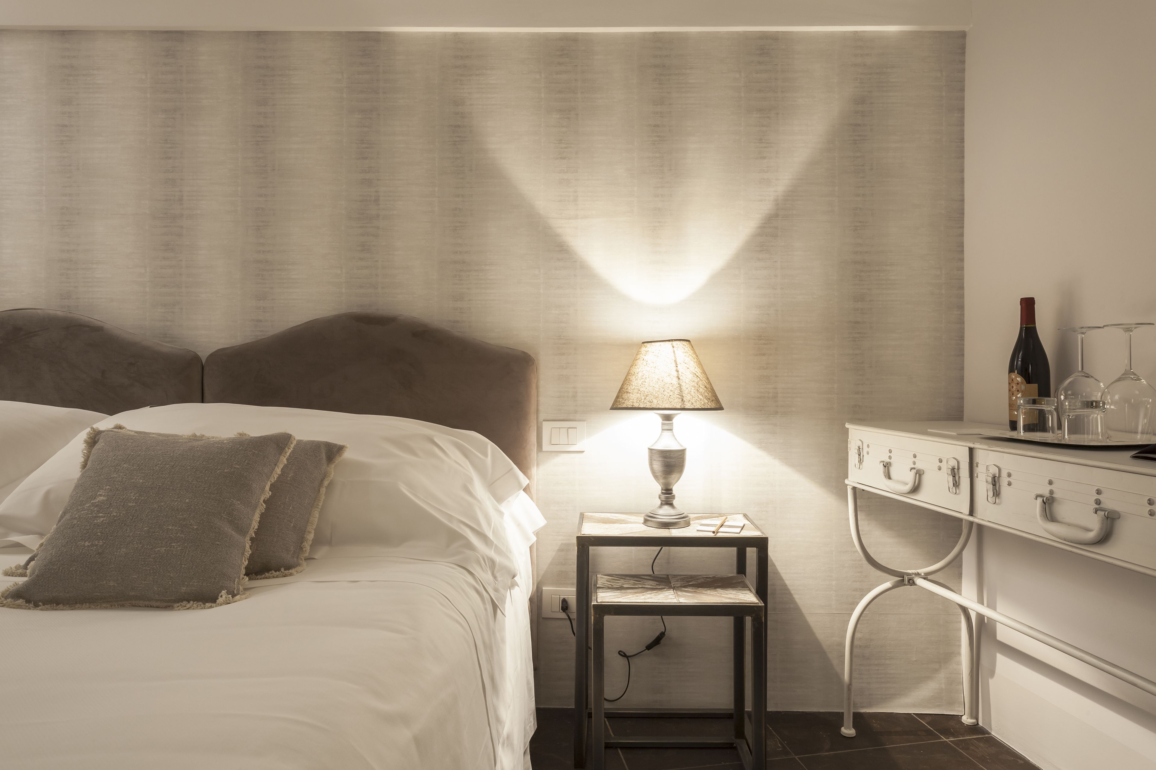 Un lit bien fait, avec des oreillers, une table de chevet avec une lampe et une commode avec des tiroirs.