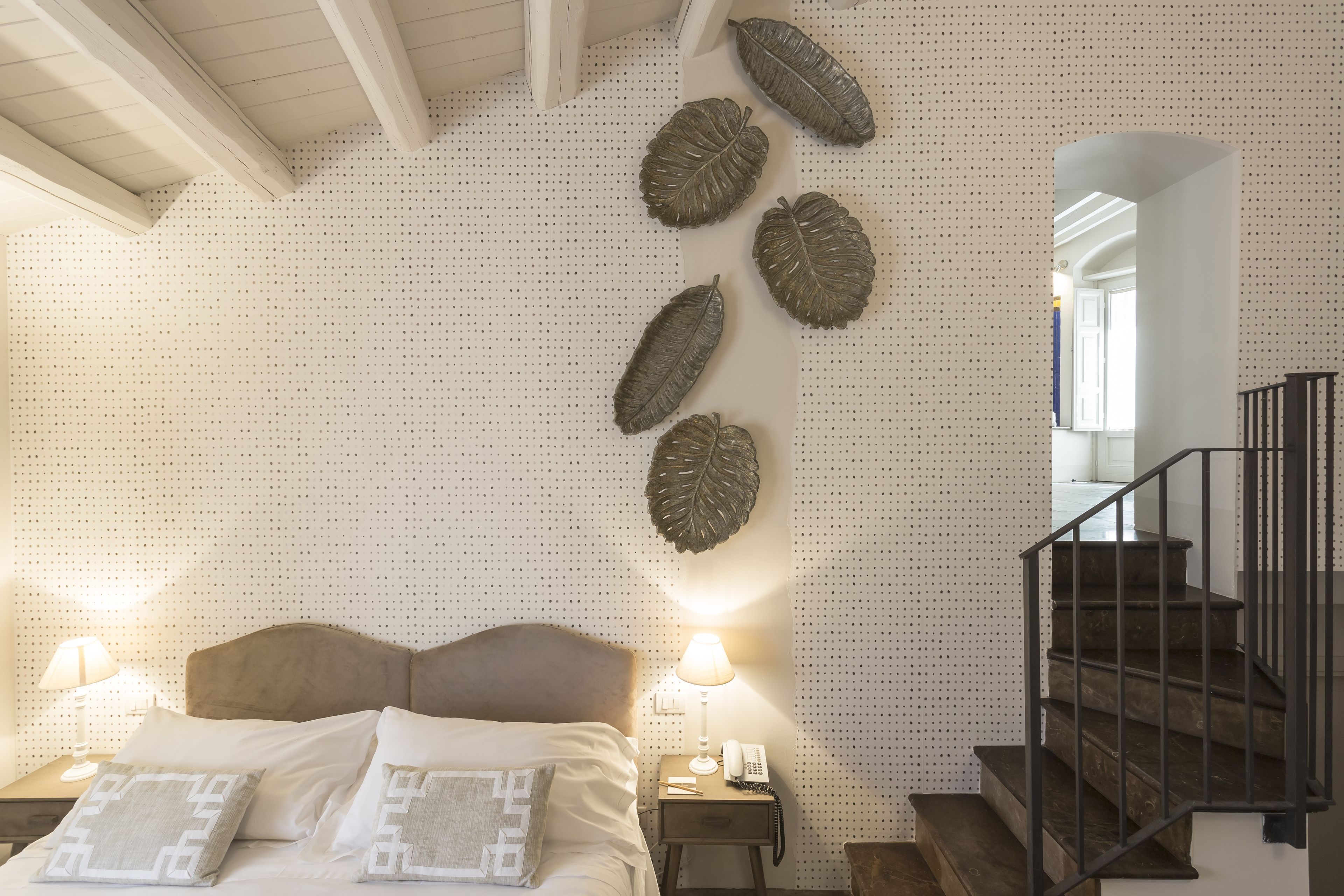 A bedroom with a bed, nightstands, a phone, and a staircase.