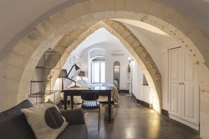 Een gewelfde gang die leidt naar een slaapkamer met een bed, een bureau en een stoel.