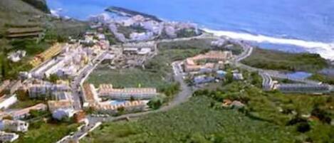An aerial view of a coastal town with buildings, roads, and greenery.