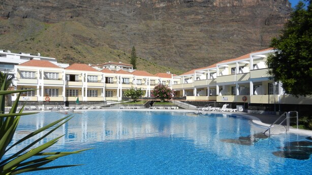 Un hôtel doté d’une piscine, de nombreux balcons et offrant une vue sur les montagnes.