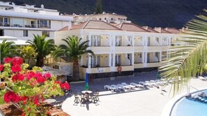 Un hôtel doté d’une piscine, de chaises longues et offrant une vue sur les montagnes.