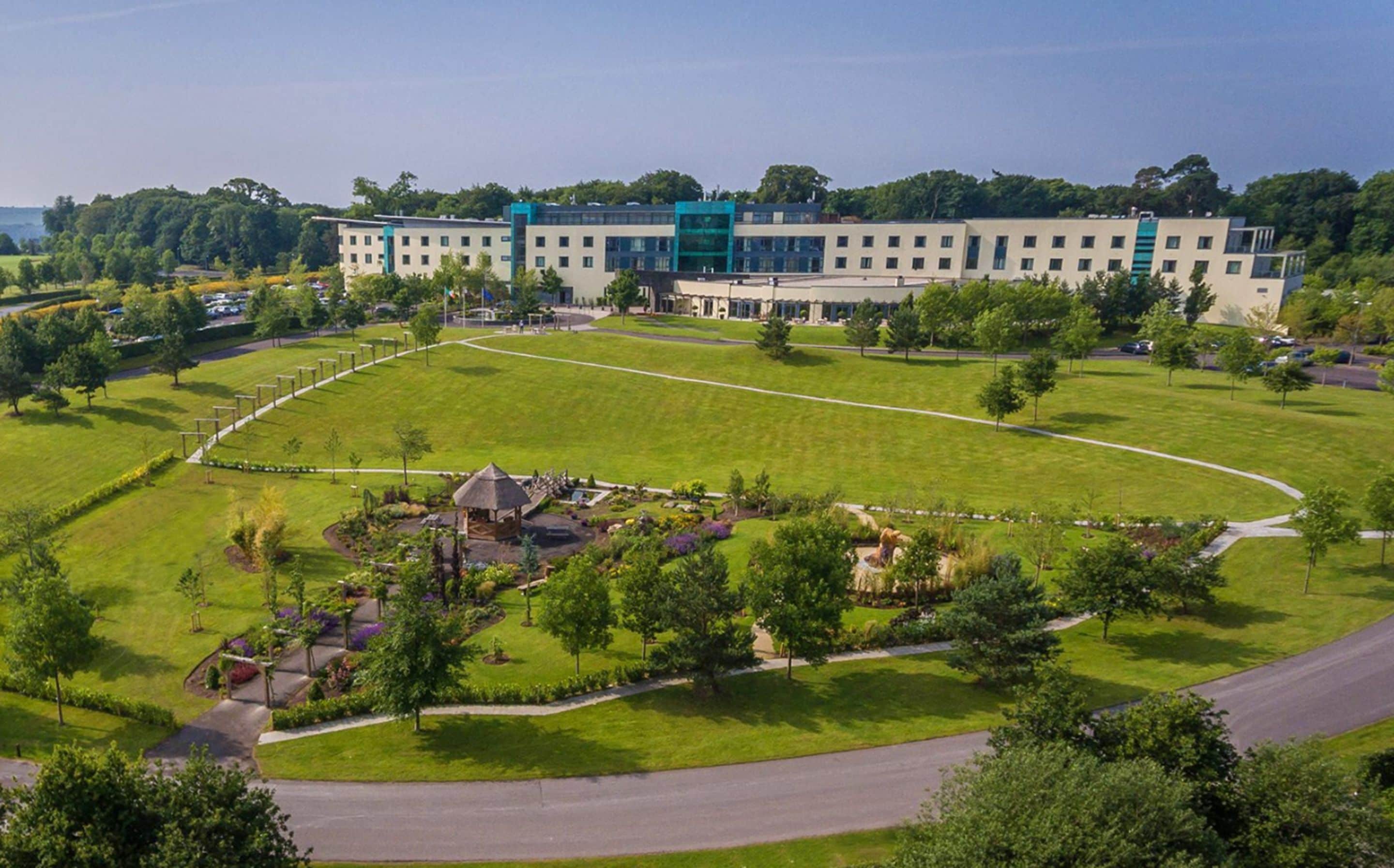 A large building with multiple floors, surrounded by a well-maintained lawn and a few trees.