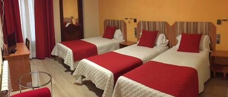 A hotel room with two beds, each with a red and white bedspread, a small table, a chair, and a mirror on the wall.